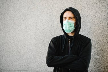 Coronavirus. Gri duvar arka planında tıbbi koruyucu maske takan bir adam. Covid-19 'u, gribi önle. Şehirde kötü hissediyorum. Birinin yardıma ihtiyacı var. Virüs, salgın hastalık, panik konsepti.