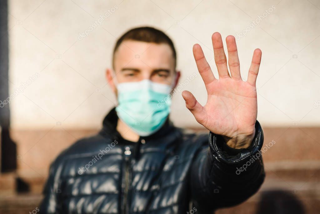 Stop the virus epidemic diseases. Coronavirus. Healthy man in medical protective mask showing gesture stop. Health protection and prevention during flu and infectious outbreak.