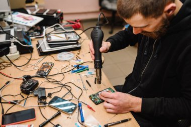 Laboratuvardaki akıllı telefon ana kartını tamir eden teknisyen. Bilgisayar donanımı, cep telefonu, elektronik, onarım, güncelleme, teknoloji kavramı. Adam atölyede telefon tamir sürecini gösteriyor.