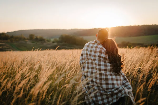 若いカップルは 立ちバック 人々は毛布で覆われ 秋には屋外で日没に抱きつく 太陽を背景にしたフィールドグラスで 友好的な家族の概念 閉じろ — ストック写真