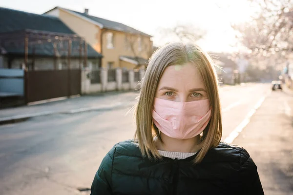 Coronavirus. COVID-19 salgını sırasında maskeli bir kız sokakta korkmuş. Coronavirus 'un tehlikeleri. Enfeksiyon yayma riski var. Burnu ve ağzı kapatıyor..