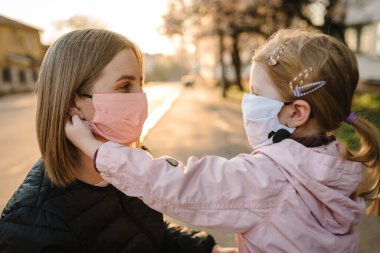 Coronavirus son konsept. Artık Coperid-19 yok. Küçük kız, anne sokakta yürürken maske takıyor. Anne, maske takan mutlu çocuğu çıkarır. Dışarıda çocuklu bir aile. Başarıyı kutlamak. Salgın sona erdi..