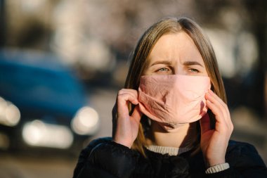 COVID-19 salgını sırasında maskeli bir kız öksürüyor ya da sokakta hapşırıyor. Coronavirus 'un tehlikeleri. Enfeksiyon yayma riski var. Burnu ve ağzı kapatıyordu. Kadın kol önleyici öksürük.