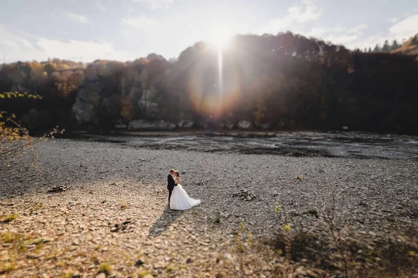 Novia Vestido Blanco Novio Pie Cerca Del Río Abrazos Sol —  Fotos de Stock