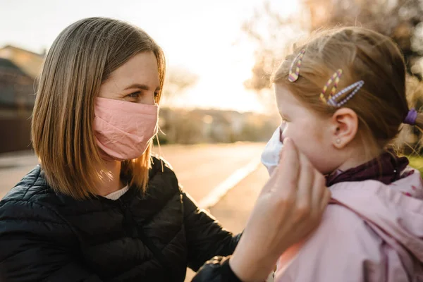 Coronavirus son konsept. Artık Coperid-19 yok. Küçük kız, anne sokakta yürürken maske takıyor. Anne, maske takan mutlu çocuğu çıkarır. Dışarıda çocuklu bir aile. Başarıyı kutlamak. Salgın sona erdi..