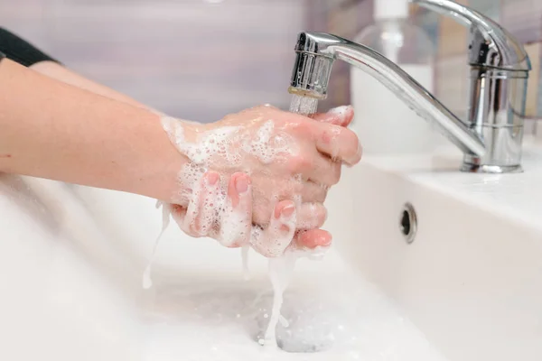 Washing hands and hygiene. Coronavirus, flu disease prevention. Wash womans hands with antibacterial soap, warm water rubbing nails and fingers in sink. Covid-19. To stop spreading coronavirus.