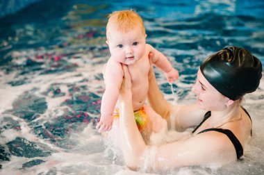 Girdap, jakuzi. Kürek havuzuna bebek dalışı. Genç anne, yüzme öğretmeni ve bilardodaki mutlu küçük kız. Küçük çocuğa yüzmeyi öğret. Suda yüzmenin ilk gününün tadını çıkar..