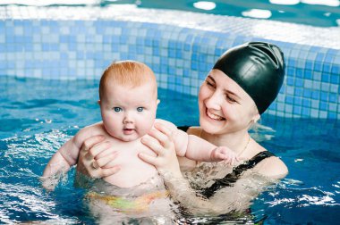 Young mother, swimming instructor and happy little girl in paddling pool. Teaches infant child to swim. Enjoy first day of swimming in water. Mom holds hand child preparing for diving. doing exercises clipart