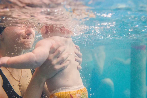 赤ちゃんを抱えてる母親 ダイビングの赤ちゃん パドリングプールでお母さん 若い母親 水泳インストラクターと水中で幸せな女の子 泳ぐために幼児を学びなさい 水の中で泳ぐのを楽しむ — ストック写真