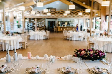 Restoran manzarası. Kutlama masası süslenmiş çiçekler, yeşillik düğün salonundaki mumlar. Yeni evliler masa örtüsüyle kaplanmış, tabaklarla servis edilmiş, çatal bıçak takımı. Kapat..