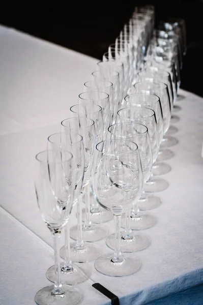Empty glass for wine and champagne stand on white table. Close up. Empty glasses for elite drinks stand in two rows.