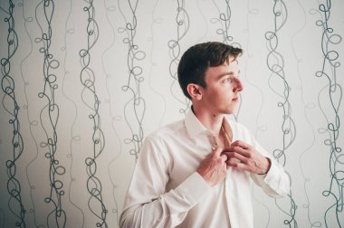 Güzel, mutlu, çıplak genç bir adam. Günaydın damat. Düğün günü. Klasik tarz. Şık bir daire. Parlak dolapların arka planına karşı. Şık erkek giyiminin bir parçası.