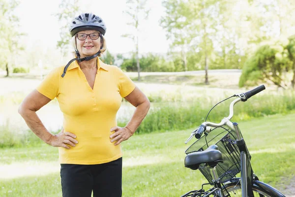 Mujer mayor activa en bicicleta y relajarse en el campo en la luz del sol brillante —  Fotos de Stock