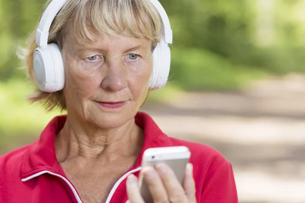 Desportivo corredor sênior mulher ouvindo música do telefone — Fotografia de Stock