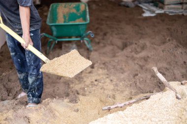 Bir işçi kürek kum içine yeni ev inşaatı için wheelborrow doldurmak için kullanın. İnşaat araçları.