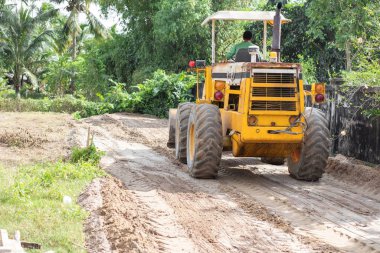 Sarı buldozer, devasa turuncu güçlü inşaat makinesi hidrolik kepçe pistonu ve kara tekerlekler yol kumlu inşaat sahasında, ağır sanayi, arka görüş.
