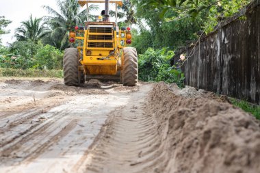 Sarı buldozer, devasa turuncu güçlü inşaat makinesi hidrolik kepçe pistonu ve kara tekerlekler yol kumlu inşaat sahasında, ağır sanayi, arka görüş.