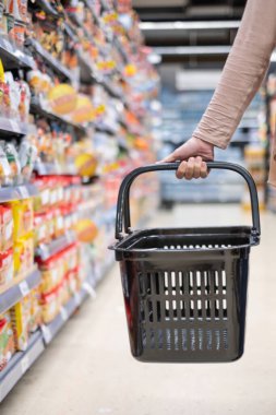 Bir kadın boş sepet içinde süper market tutuyor
