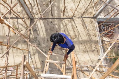 Man wearing boot using temporary wood stair in construction site to go up and down.
