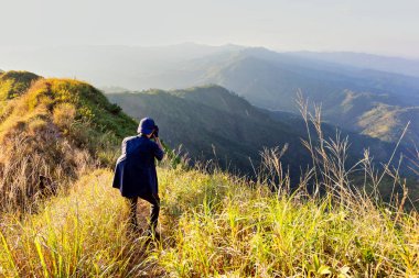 Genç yürüyüşçü, terkking yolunda fotoğraf çekiyor. Fotoğrafçı dağ zirvesinde fotoğraf çekiyor..