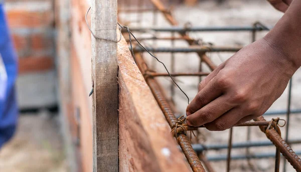 A worker using steel wire and pincers to secure steel bars, prep — Stock Photo, Image