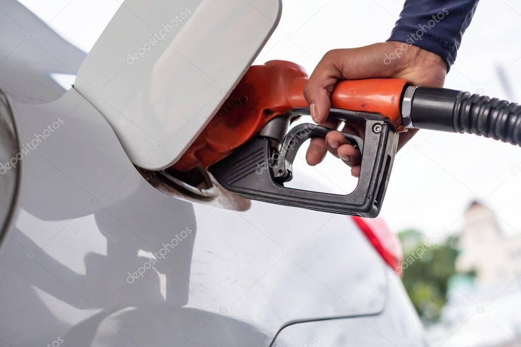 Man filling up his white car with petroleum.
