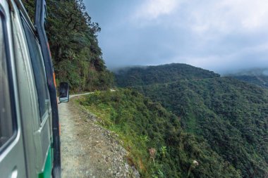 Death Road - July 25, 2017: Tour bus travelling in the Yungas ro clipart