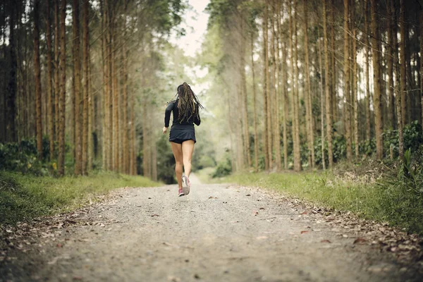 Woman jogging on a warm day, outdoors. Young woman with black suit. Lifestyle. Woman in the middle of nature