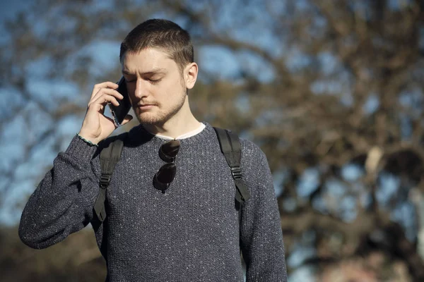 Casual young man speaks on the phone looks angry an serious