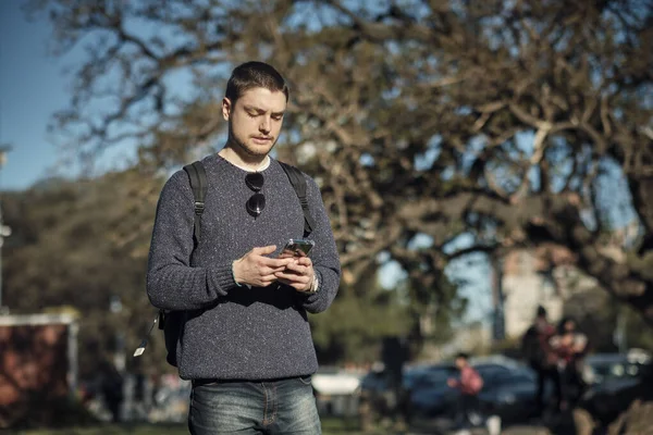 Casual young man sending a message from his cell phone while walking.