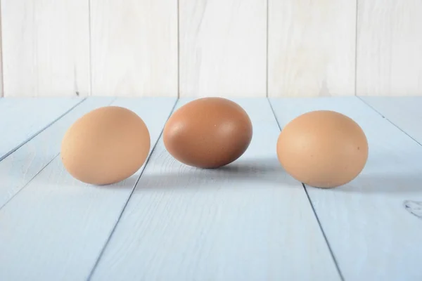 Tre uova marroni su legno blu — Foto Stock