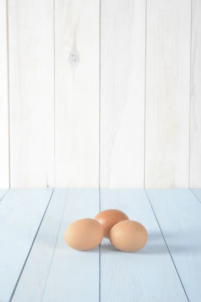 Drie bruine eieren boven blauw hout — Stockfoto
