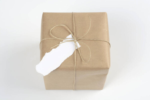 Piece of white paper in a closed gift package with rope and bow on white background