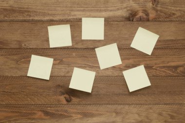 Kahverengi ahşap arka planda notlar veya varsayımlar, kare kağıtlar