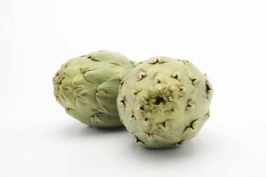 Beyaz arka planda çiğ enginarlar, sebzeler.