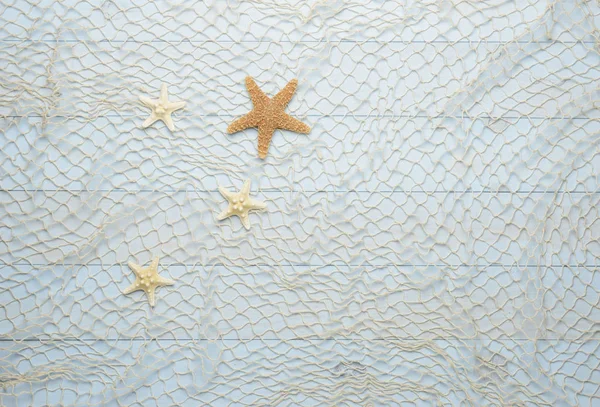 Estrella de mar sobre fondo azul de madera con red de pesca — Foto de Stock