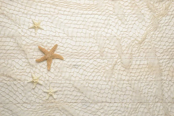 Морские звезды на белом деревянном фоне с рыболовной сетью — стоковое фото