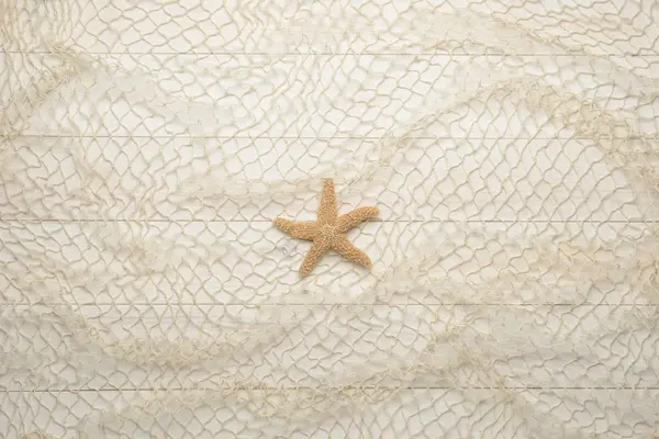 Estrella de mar sobre fondo de madera blanca con red de pesca — Foto de Stock