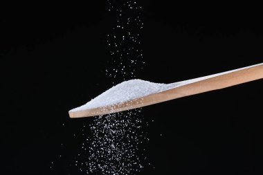 Siyah arka planda kaşığa düşen şeker