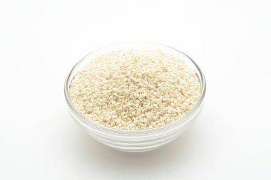 Beyaz arka planda cam bir kasede beyaz susam tohumu