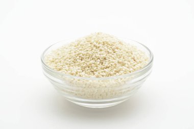 Beyaz arka planda cam bir kasede beyaz susam tohumu