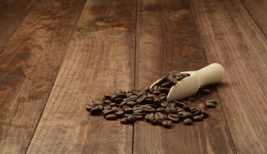 Kahve çekirdekleri ve ahşap arka planda ahşap kaşık.