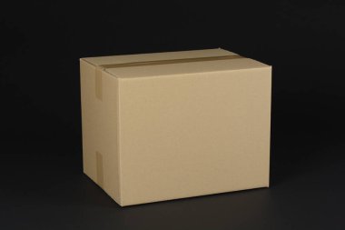 Closed cardboard box on black background clipart