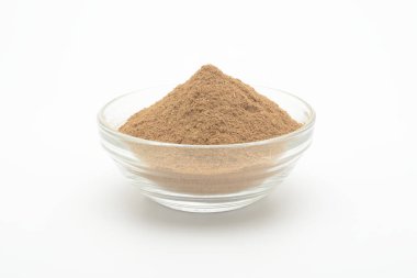 Beyaz arka planda cam bir kasede yer tarçın.