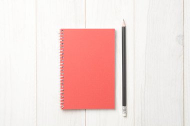 Beyaz ahşap zemin üzerinde defter ve kalem, kapalı kitap