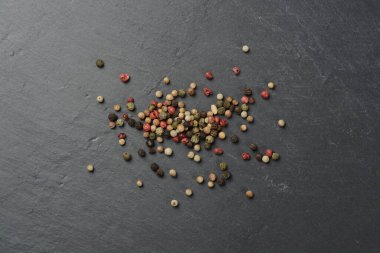 Siyah taşın üstüne beş çeşit biber, üst görünüm.