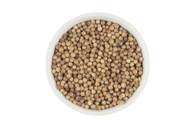 Beyaz arka planda beyaz seramik bir kasede kişniş taneleri, üst manzara.