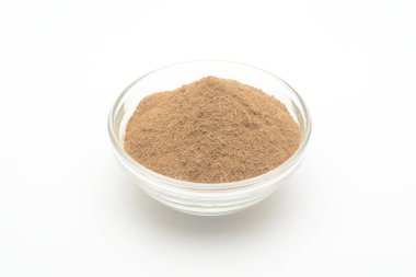 Beyaz arka planda cam bir kasede yer tarçın.