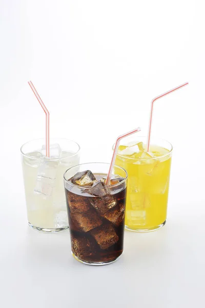 Cola, orange and lemon soda in glass with straw on white background. Refreshing drinks on white background.