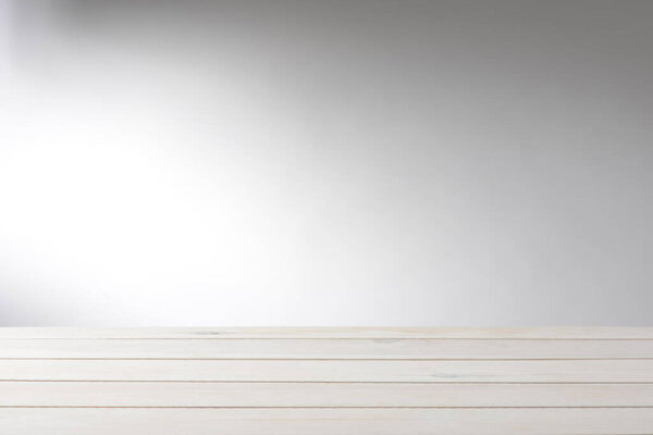 Empty white wooden table background, with light effect on the wall